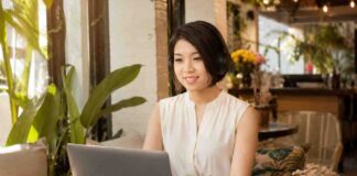 Woman works on a laptop with headphones in a sunny café.